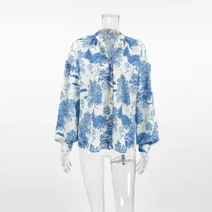 Detail of blue and white landscape print blouse with lantern sleeves and stand collar.
