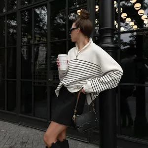 Stylish woman wearing a striped half-zip knit sweater in a modern urban cafe setting