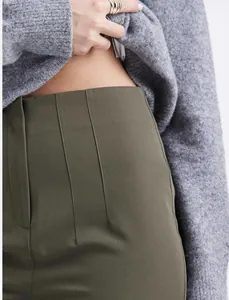 Close-up detail showing the high-waisted design and fine stitching of olive green tailored trousers.