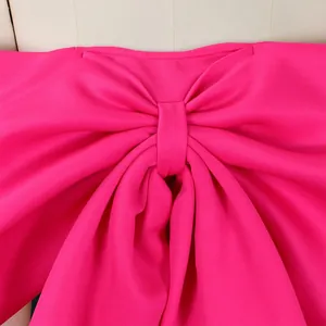 Dettaglio macro di un nodo a fiocco fucsia vibrante su un top sexy da donna con spalle scoperte