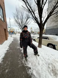 Full body view of vintage floral embroidered one-piece ski suit in a snowy street setting.