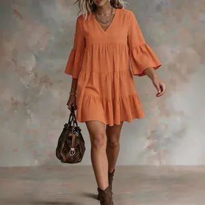Detailed view of fashionable orange tiered mini dress with V-neck and flared sleeves