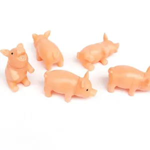 Gros plan de plusieurs jouets pour chiens en caoutchouc rose en forme de cochon siffleur.