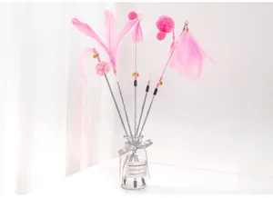 Dettaglio ravvicinato di bastoncini per gatti con piume rosa, campanelli e nastri