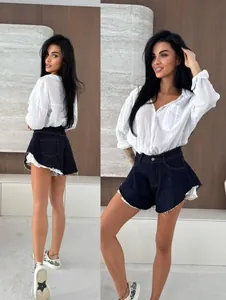 Dettaglio di pantaloncini in denim scuro a vita alta con orlo a balze sfrangiato