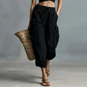 Detail view of black high-waisted cargo pants featuring multiple utility pockets and drawstring.