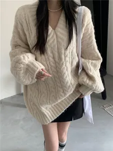 Dettaglio ravvicinato della trama di un maglione a trecce spesse crema con scollo a V