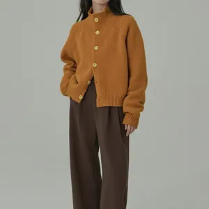 Detalle de cárdigan de punto amarillo mostaza con cuello alto y botones de textura