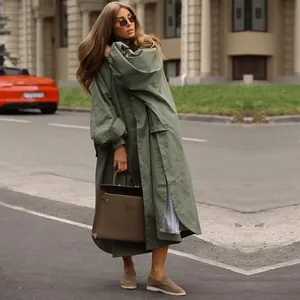 Full body view of an oversized green trench coat with lantern sleeves in a street setting.