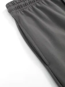 Gros plan détaillé d'un pantalon de sport gris avec taille élastique et poche latérale.