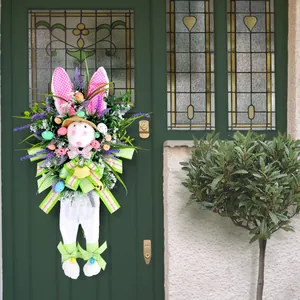 Ghirlanda pasquale festosa con coniglietto di peluche e uova colorate su porta verde