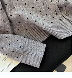 Close-up of grey polka dot knit cardigan showing ribbed cuffs and soft fabric texture.