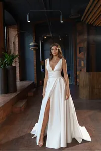 Elegant white deep V-neck evening gown with high leg slit and sleek open back design.