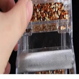 Detaillierte Nahaufnahme eines Futterautomaten aus Acryl mit Vogelfutter Mischung