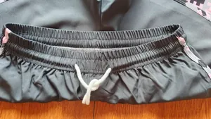 Detailed close-up of elastic waistband and white drawstring on black women's sports shorts