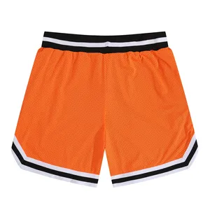 Close-up of orange mesh basketball shorts with striped elastic waistband and hem.