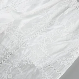 Vue détaillée d'un tissu en coton blanc avec broderie florale ajourée complexe.