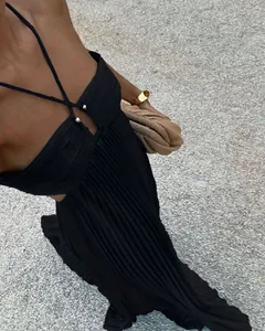 Close-up of elegant black pleated halter maxi dress with criss-cross neckline detail.
