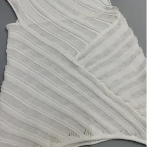 Detailed macro shot of white knitted dress featuring diagonal ribbing and hollow-out texture