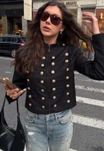 Femme élégante portant une veste militaire noire avec des boutons dorés dans la rue