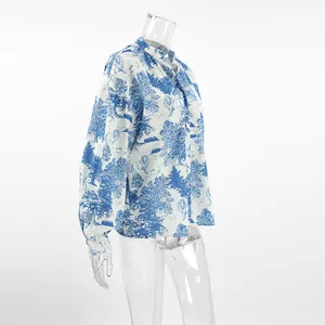 Detail view of women's white blouse featuring blue landscape print and lantern sleeves
