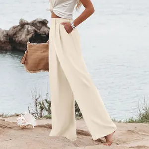 Elegante dettaglio di pantaloni larghi color crema a vita alta da donna in spiaggia