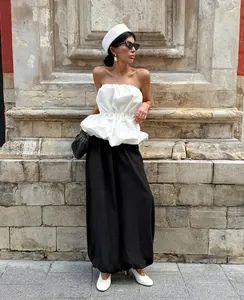 Model in street style posing with a white strapless peplum top and black bubble trousers