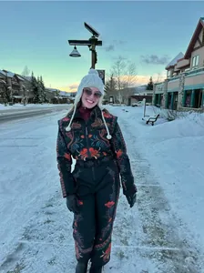 Model in vintage floral embroidered ski suit on a scenic snow-covered mountain street.