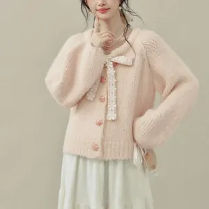 Dettaglio di un morbido cardigan in maglia rosa con fiocco e bottoni floreali.