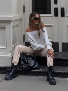 Chic white off-the-shoulder knitted sweater for women styled in urban street setting