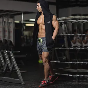 Muscular athlete wearing a black sleeveless hooded vest in a fitness gym setting