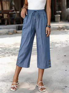 Modische lockere blaue Tencel-Denim-Caprihose mit Kordelzug und Knopfdetails am Saum.