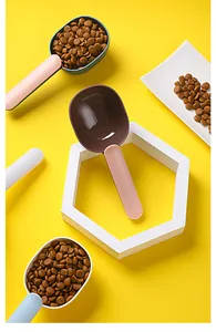 Palas de plástico de colores para comida de perros y gatos en detalle sobre fondo amarillo