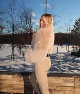 Woman wearing a light khaki ski suit with a luxurious faux fur collar in a snowy landscape
