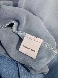 Detail shot of the 100% polyester fabric and care label on this blue denim-look dress