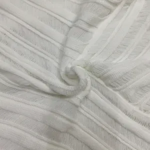 Macro detail of white ribbed knit fabric texture showing intricate vertical patterns.