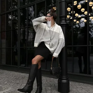 Fashionable striped half-zip oversized sweater styled with black boots and handbag.