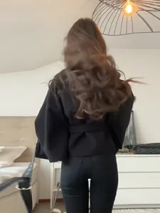 Vista trasera de una elegante chaqueta tipo capa negra con cinturón para mujer entallada