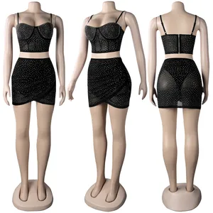 Vista detallada de un conjunto negro de dos piezas con pedrería en un maniquí de costura