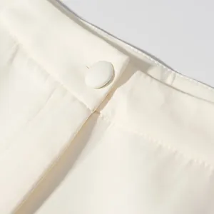 Macro detail view showing the waistband and fabric-covered button of cream lantern pants