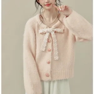 Primo piano di un morbido cardigan rosa con un grande fiocco di pizzo e bottoni a stella