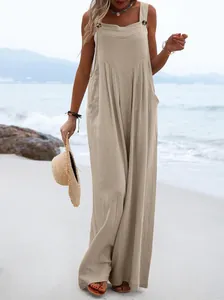 Modelo con un mono beige sin mangas de pierna ancha en una playa bajo el sol intenso