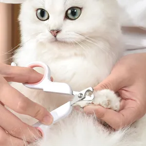 Professional white and pink pet nail clipper tool being used on a fluffy white cat paw