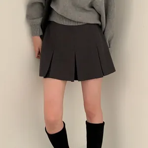 Dettaglio di una minigonna a pieghe grigio scuro con un accogliente maglione grigio.