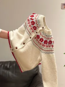 Close-up of a vintage Fair Isle knit cardigan in off-white with red floral patterns.