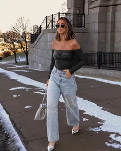 Elegant black off-the-shoulder long sleeve top with sequin details on a model