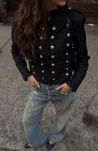 Détail d'une veste noire style militaire avec boutons dorés décoratifs et épaulettes
