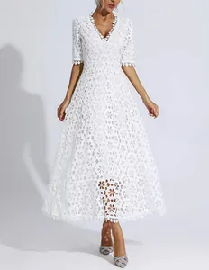 Detailed macro view of the intricate floral lace embroidery on a white V-neck midi dress