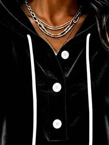 Close-up detail of women's black velvet hoodie featuring white buttons and drawstrings