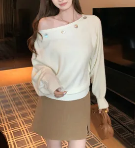 Mujer elegante con un suéter de punto blanco con hombros descubiertos y botones de colores